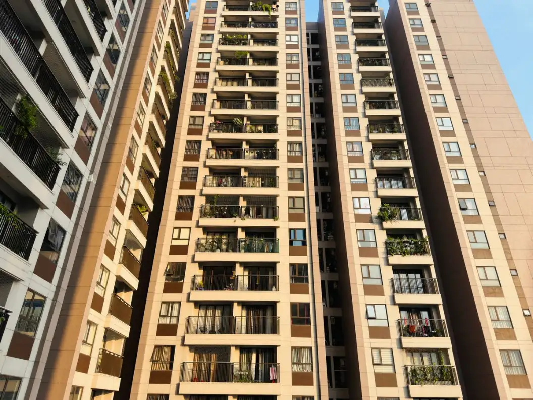 High-rise apartment buildings with balconies in an urban setting under a clear blue sky, emphasizing modern architecture.