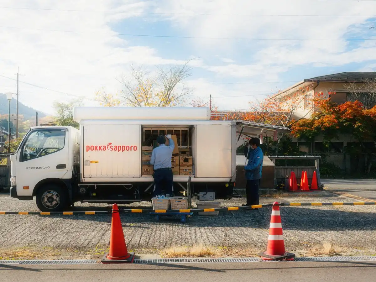 A delivery truck being unloaded in a Japanese suburb during autumn.