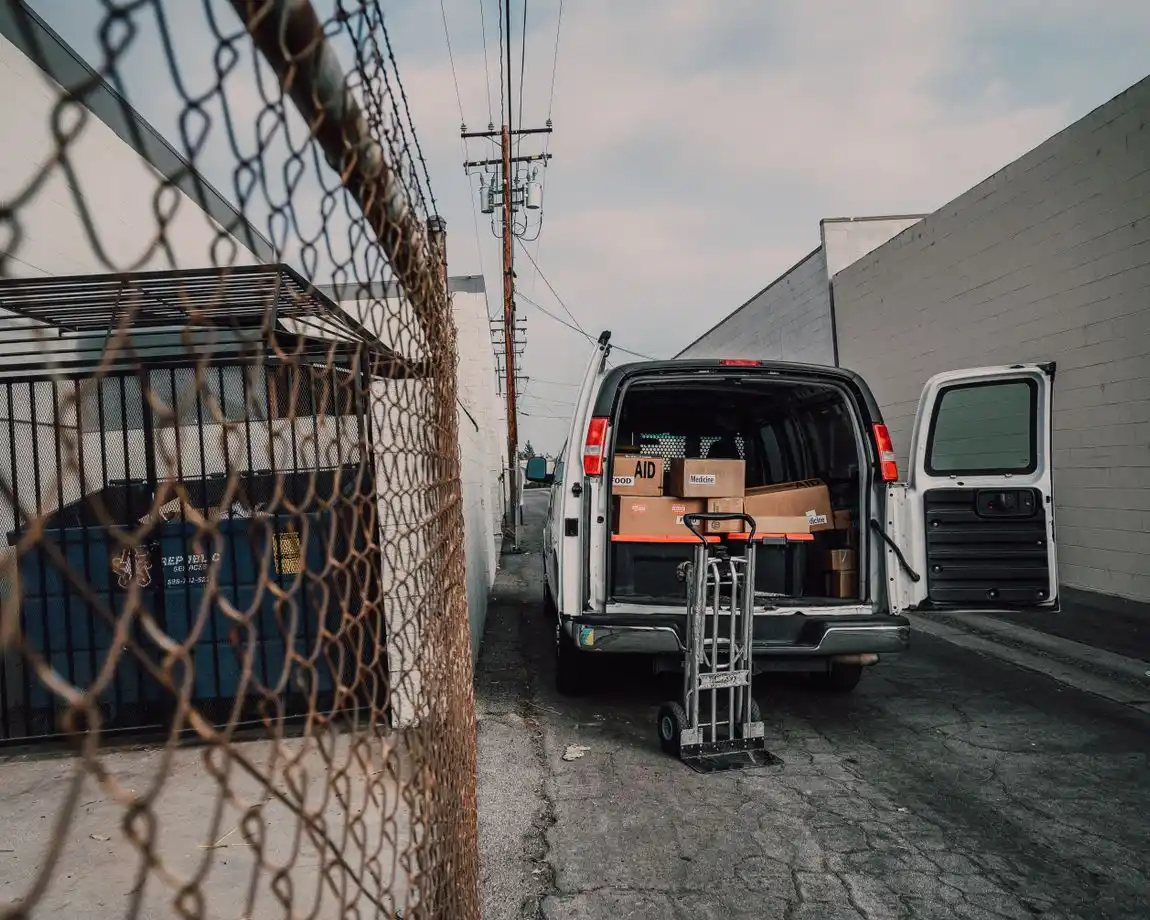 An open van loaded with boxes in an alley, ready for donation deliveries.