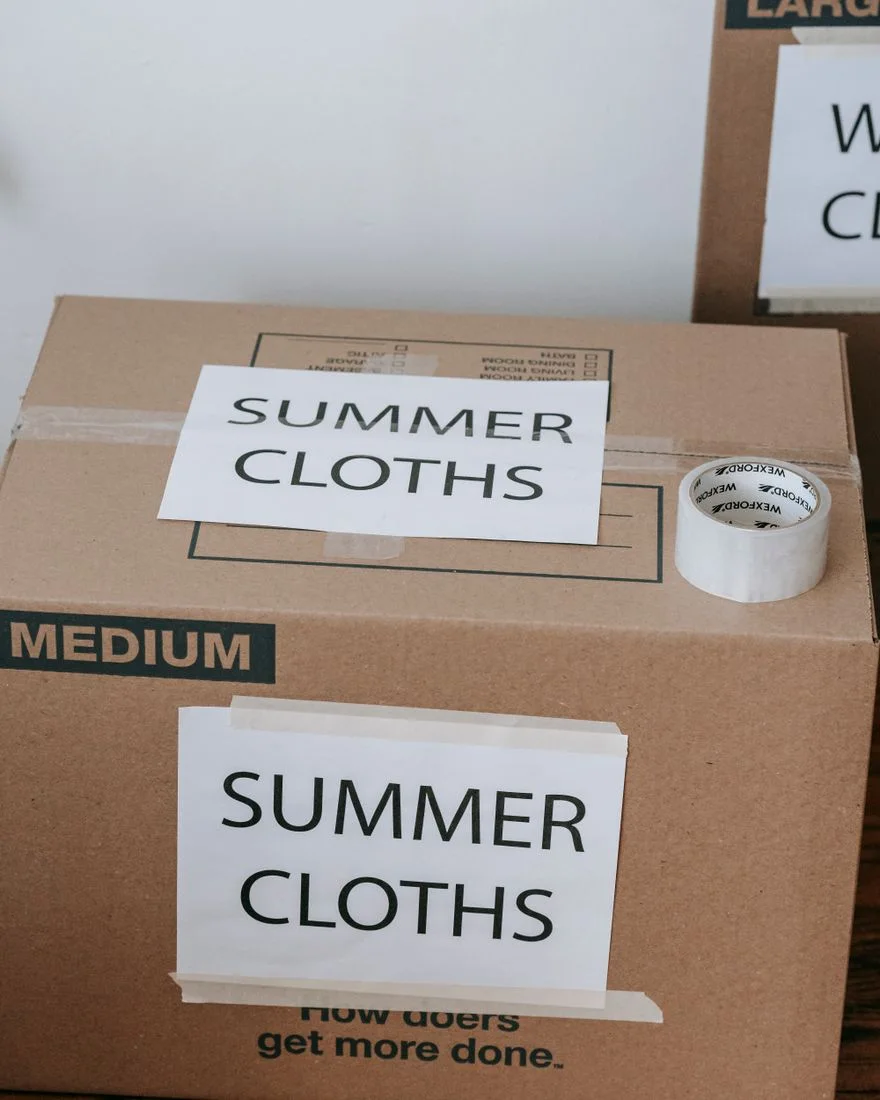 Labeled cardboard boxes for summer clothes ready for moving or storage, with packing tape and labels.
