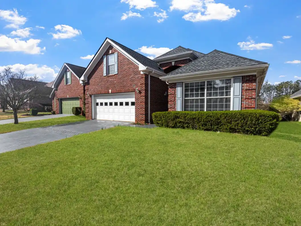 Lovely red brick suburban house with a well-maintained lawn under a bright blue sky.