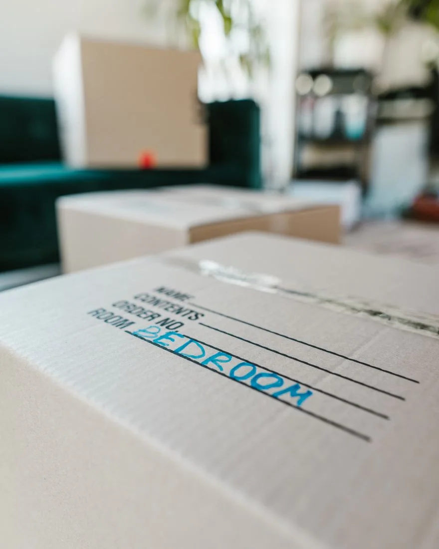 Packed cardboard box labeled 'Bedroom' indoors, ready for moving.